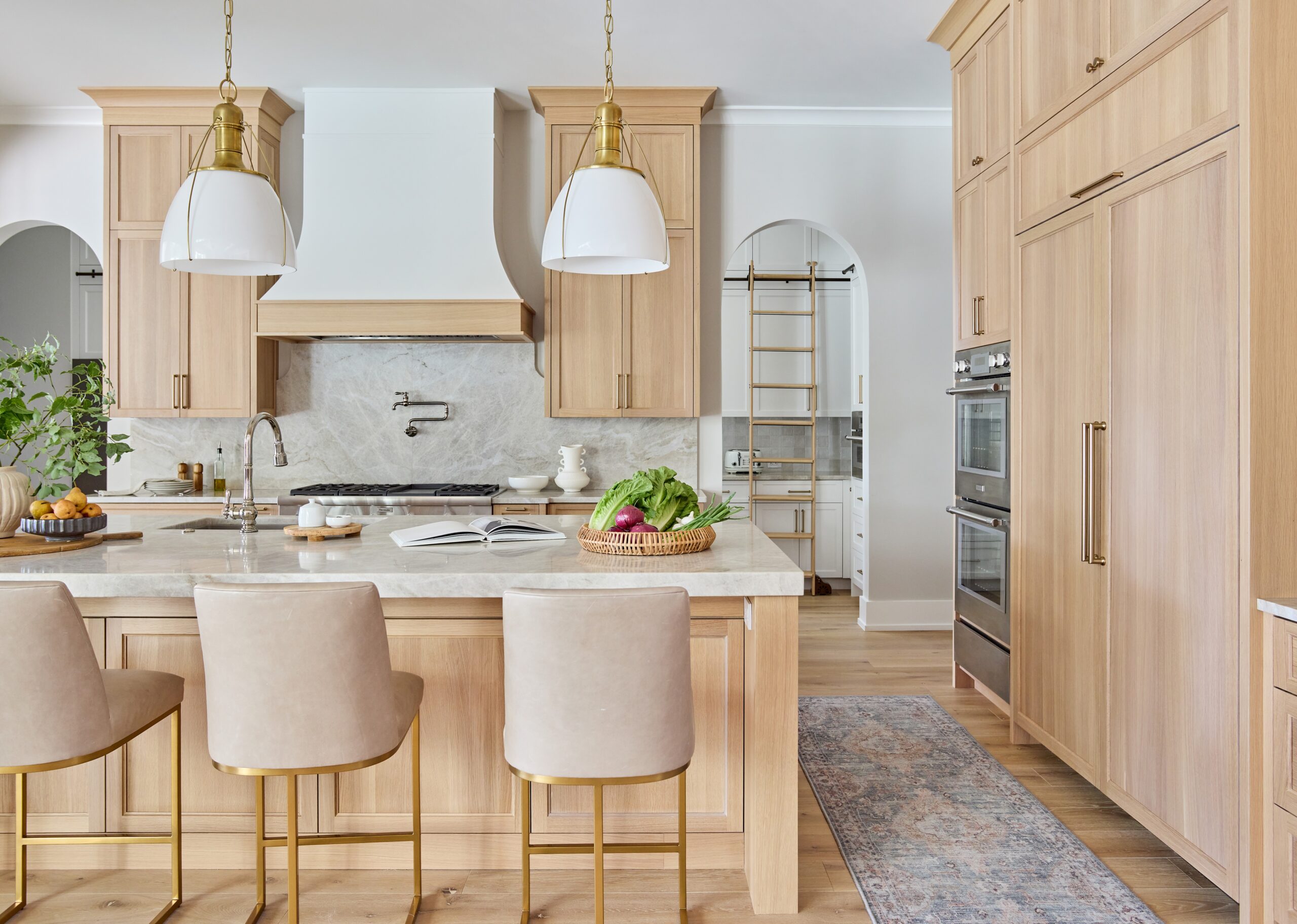 Luxury custom kitchen island with white oak cabinetry and marble waterfall countertop.