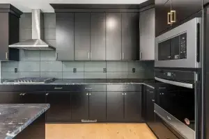 Modern black flat panel kitchen cabinets with all-plywood construction and gold hardware in a luxury kitchen.