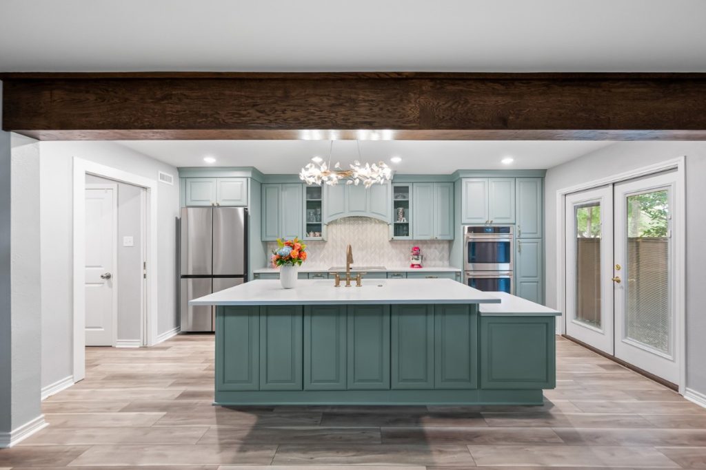 Custom sage green kitchen cabinets with raised panel doors, stacked crown molding, and a professional-grade multi-level island.