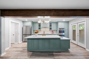Custom sage green kitchen cabinets with raised panel doors, stacked crown molding, and a professional-grade multi-level island.