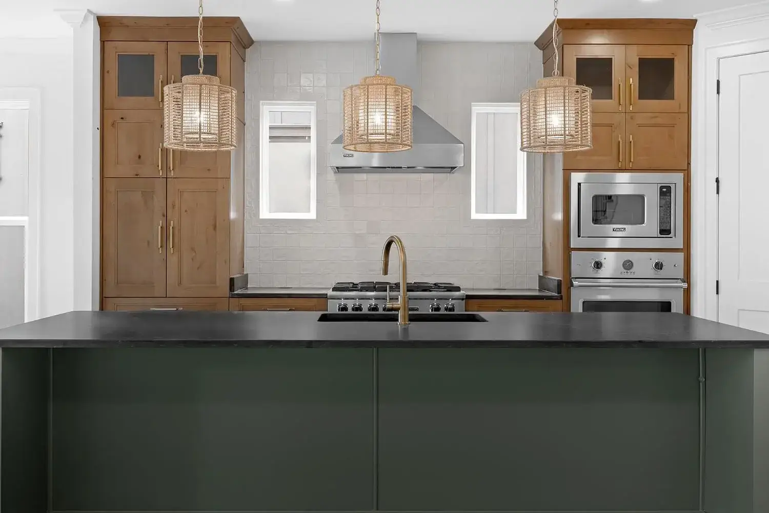Custom two-tone kitchen featuring stained wood shaker cabinets, a matte green kitchen island, and professional-grade integrated appliances.