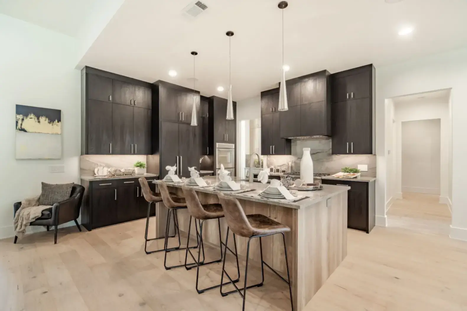 Open concept kitchen with dark wood kitchen cabinets and a light oak island with marble countertops.