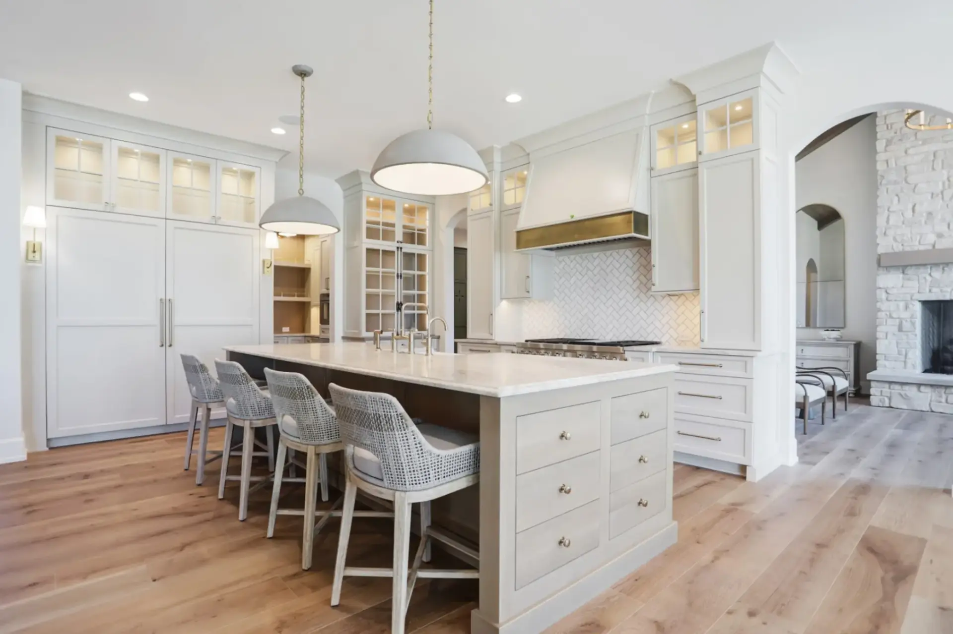 Integrated built in refrigerator cabinet with white shaker panels and custom brass hardware in a luxury kitchen.