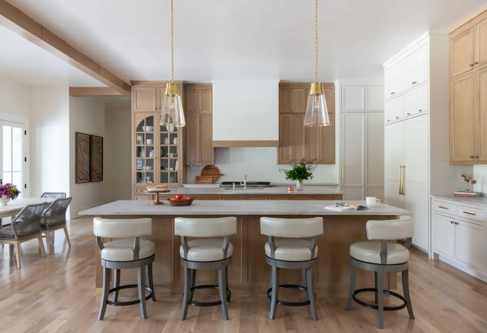 A wide-angle shot of a luxury kitchen design by ALLAND featuring white oak kitchen cabinets and a two-tone double island layout.