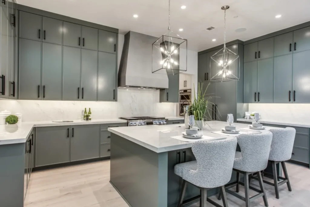 Close-up of skinny shaker kitchen cabinets in muted green with a marble waterfall island.
