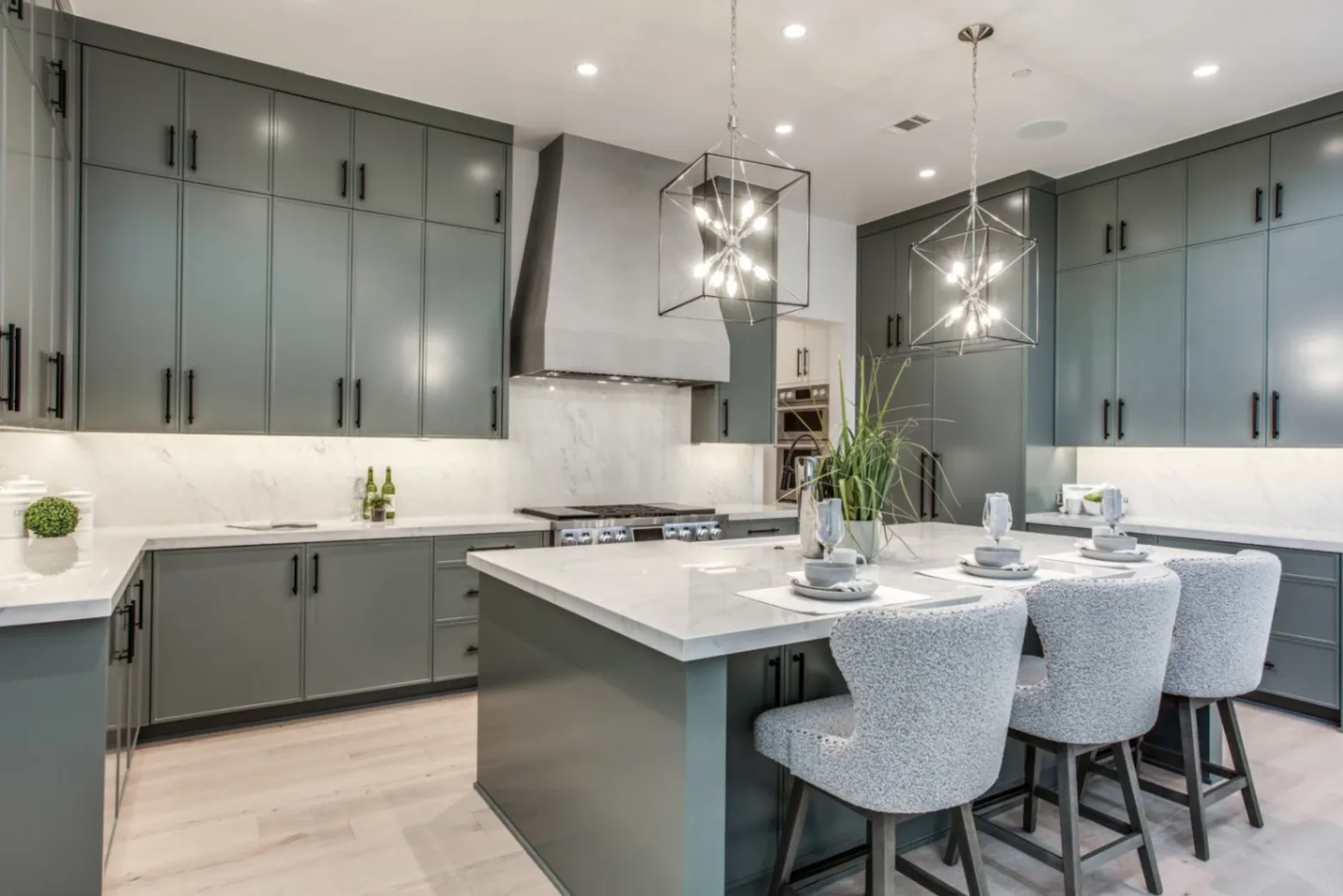 Close-up of skinny shaker kitchen cabinets in muted green with a marble waterfall island.