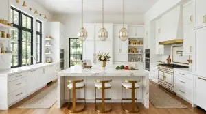 Modern white and gold kitchen featuring custom frameless cabinetry with white marble island and elegant gold pendant lights.