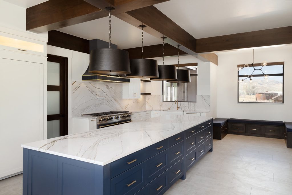 Luxury coastal kitchen featuring white lacquered shaker cabinets and an oversized navy blue kitchen island with premium white quartz countertops.