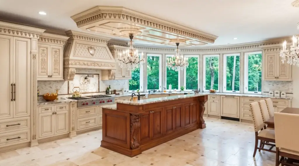 Grand estate luxury traditional kitchen featuring intricate hand-carved crown moldings, glazed raised-panel cabinets, ornate corbels, and a heavy timber contrasted central island.