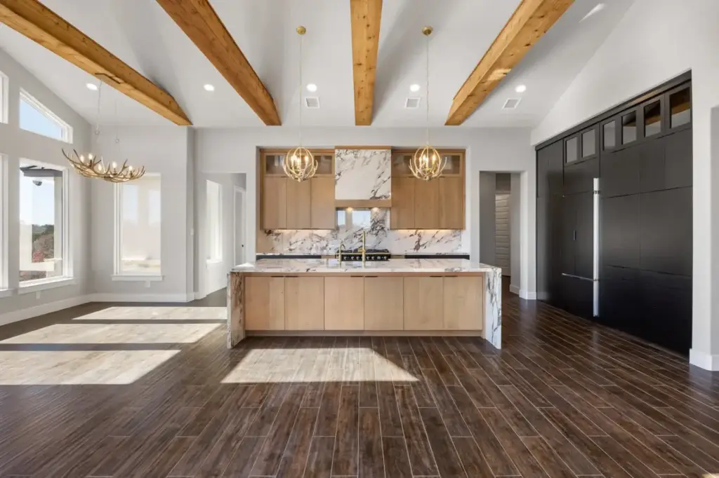 Two-tone modern mountain kitchen highlighting an open layout with matte black kitchen cabinets and a natural marble waterfall kitchen countertop.