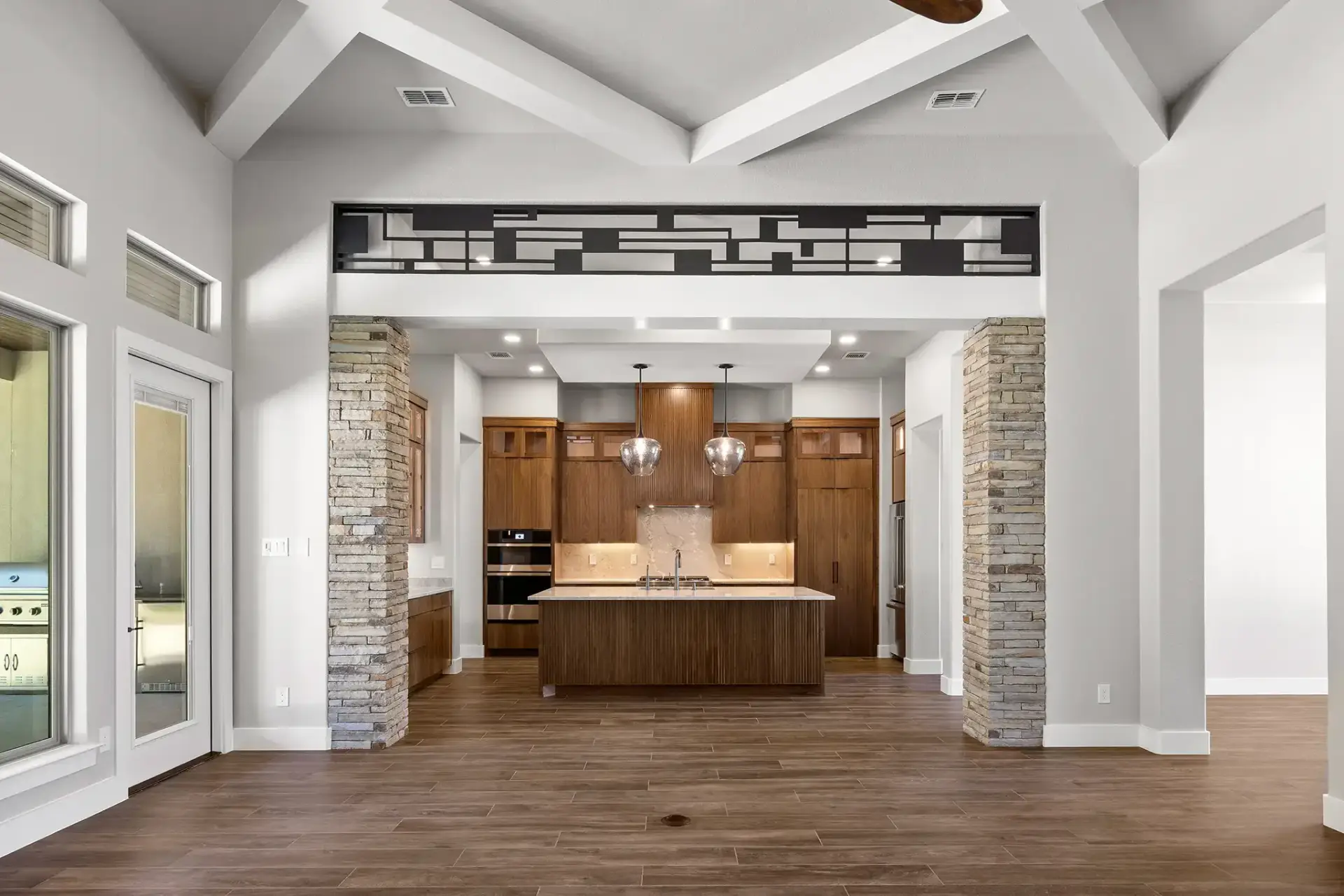 Contemporary open layout kitchen featuring integrated natural walnut kitchen cabinets, a fluted wood island, and a hidden pantry door in kitchen.