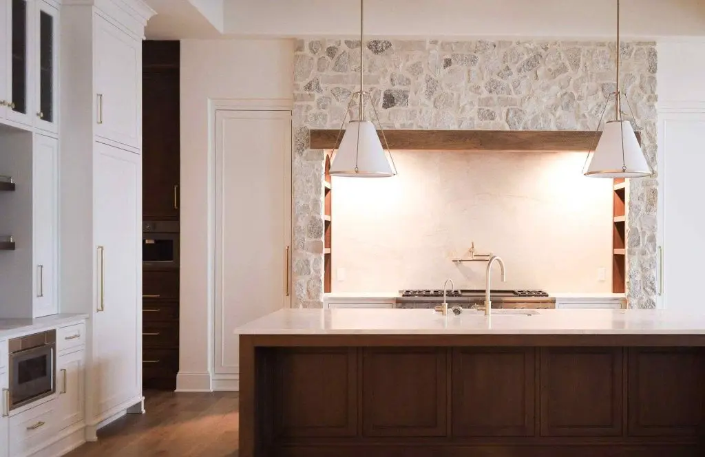 Farmhouse style kitchen range flanked by symmetrical white inset cabinets with integrated arch shelving under a rustic stone alcove.