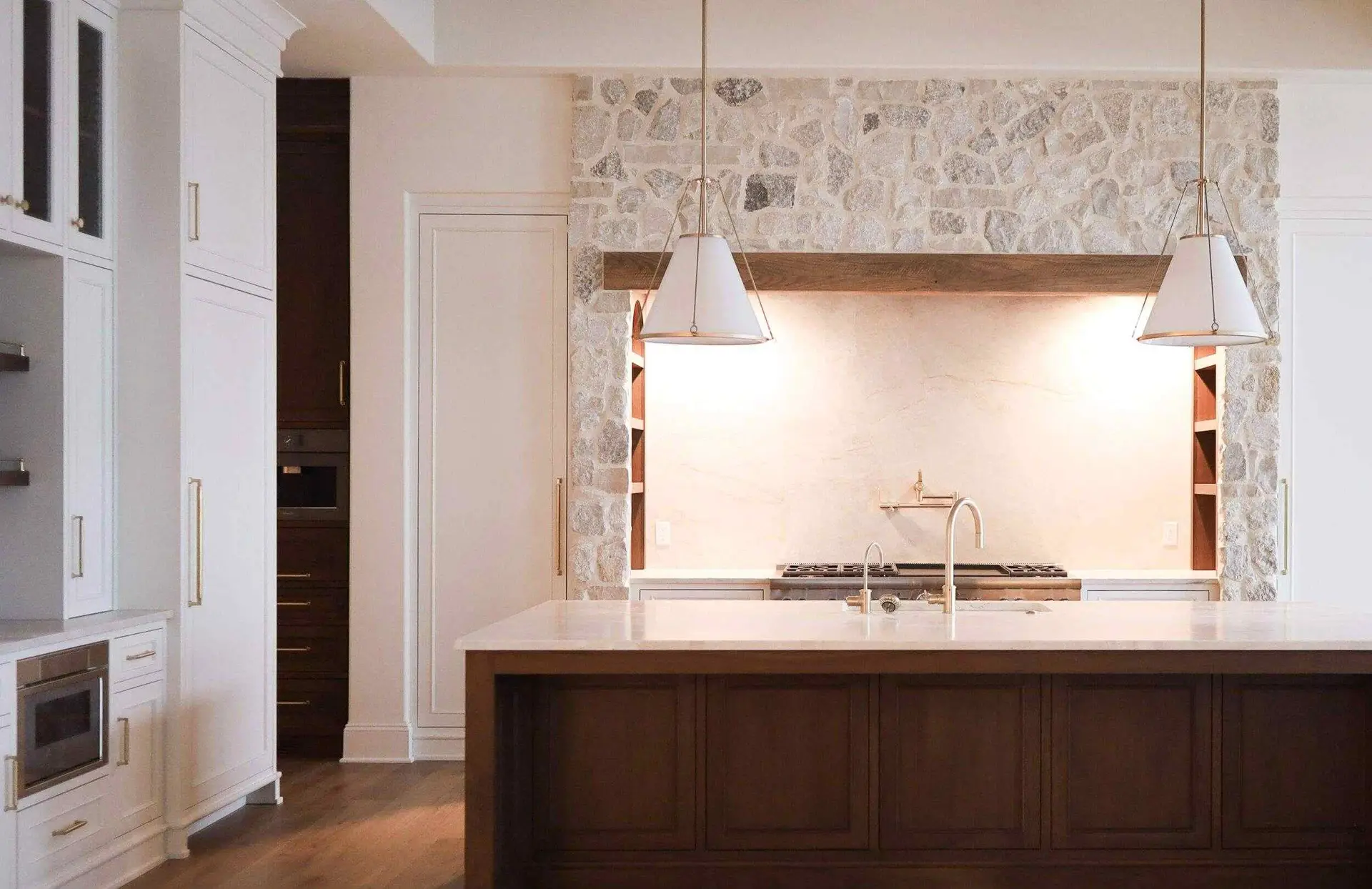 Farmhouse style kitchen range flanked by symmetrical white inset cabinets with integrated arch shelving under a rustic stone alcove.