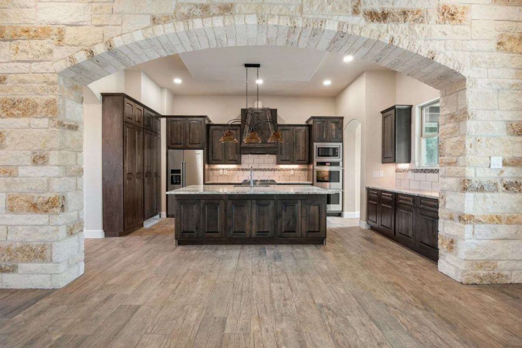 Tall custom appliance storage tower showcasing kitchen cabinets dark wood materials surrounding integrated professional double wall ovens.
