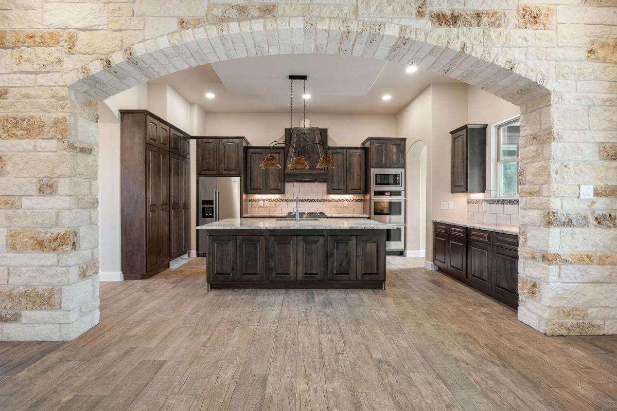 Tall custom appliance storage tower showcasing kitchen cabinets dark wood materials surrounding integrated professional double wall ovens.