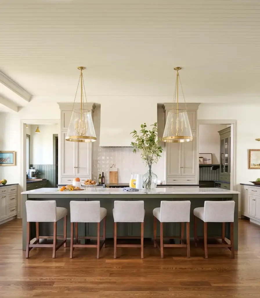 Luxury great room perspective showcasing a beige and green kitchen layout with dual glass pendant lights over a green island.
