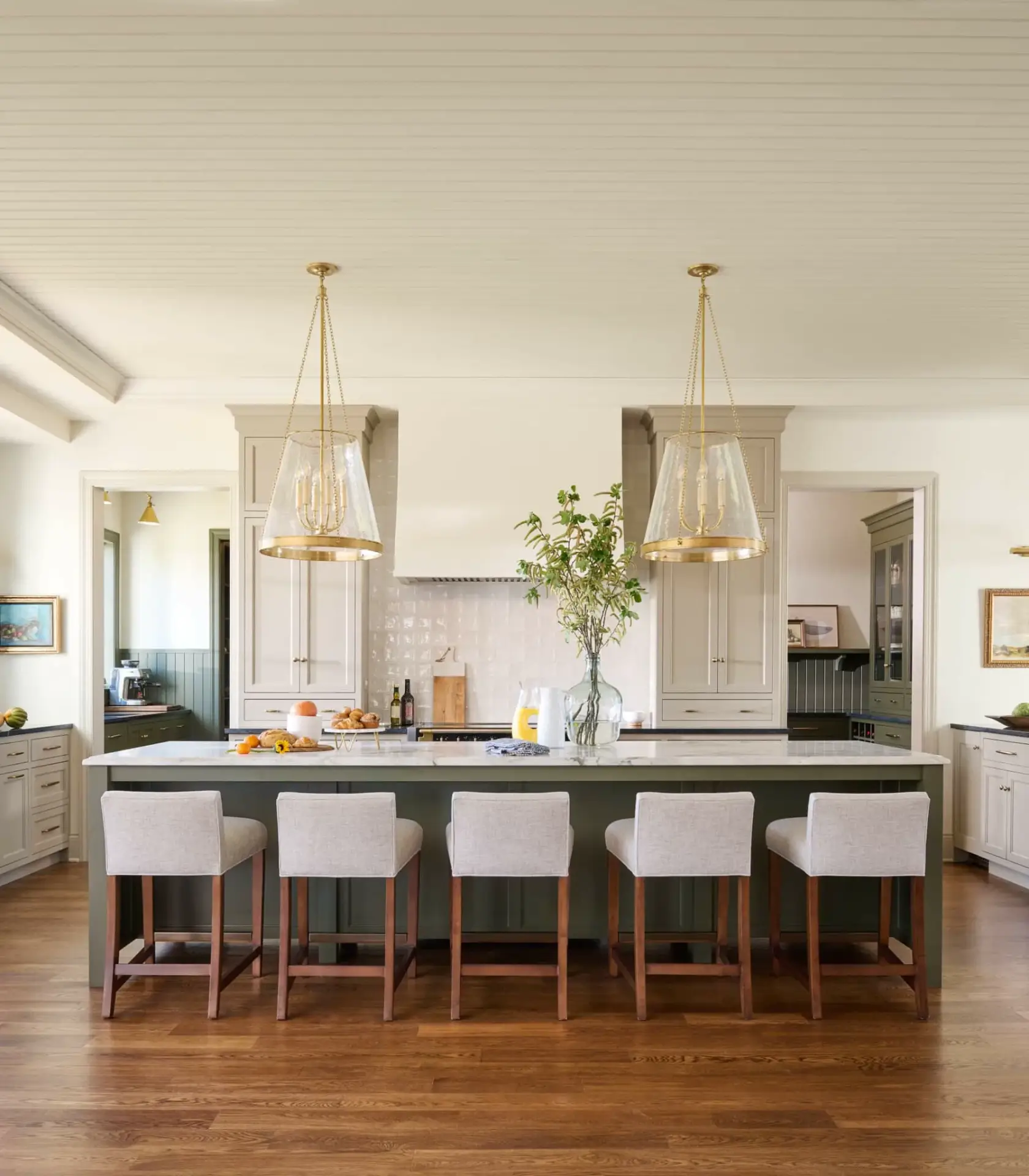 Luxury great room perspective showcasing a beige and green kitchen layout with dual glass pendant lights over a green island.