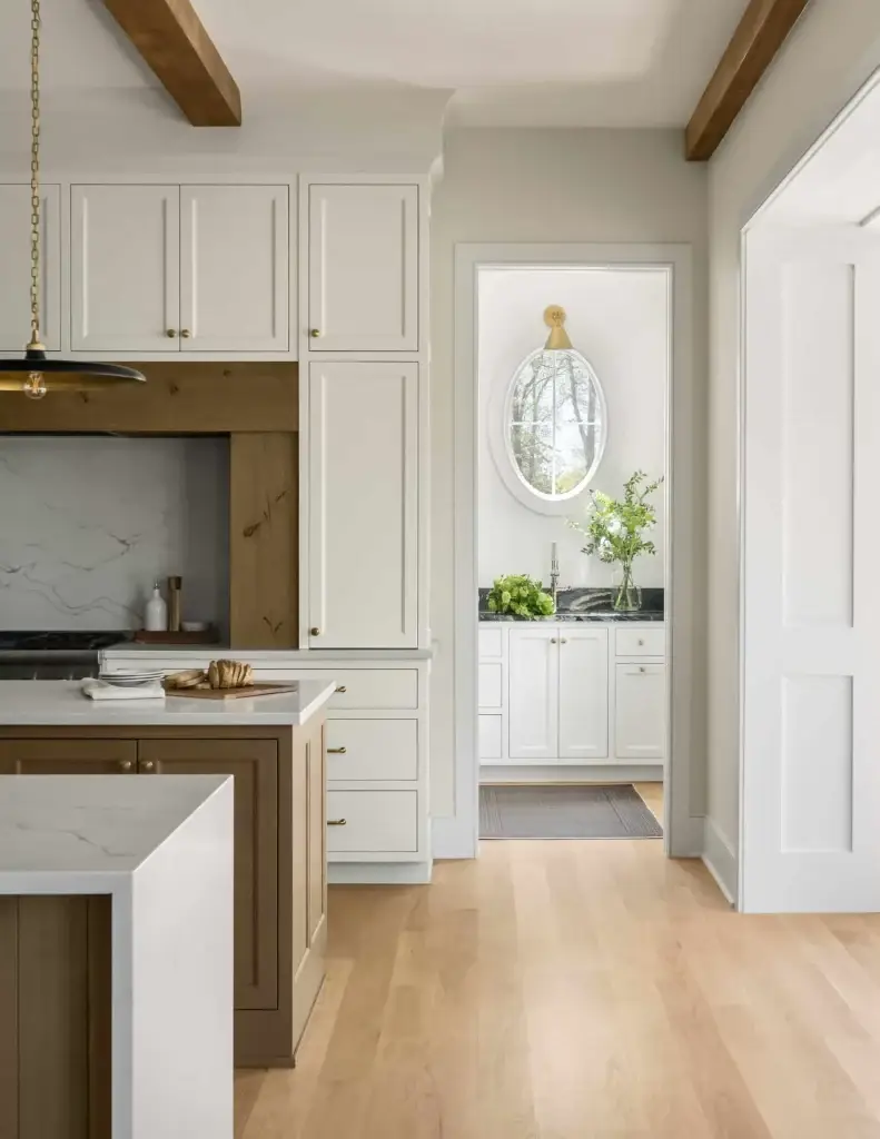 Side perspective focusing on premium custom inset kitchen cabinets flanking an arched entry path into a rear scullery.