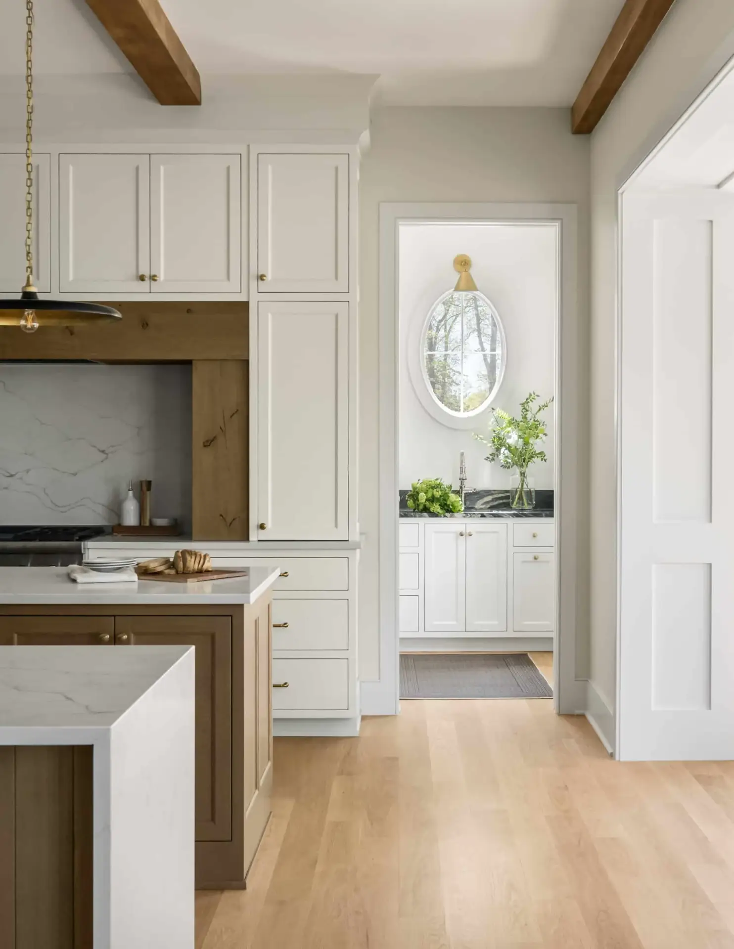 Side perspective focusing on premium custom inset kitchen cabinets flanking an arched entry path into a rear scullery.