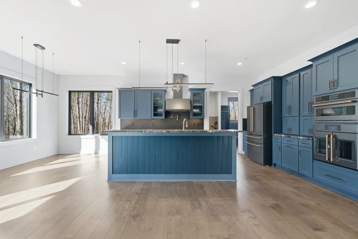 Symmetrical front perspective focusing on a custom dark blue kitchen cabinets island assembly topped with thick quartz slabs.