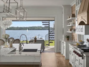 Expansive wide landscape shot of a custom modern coastal kitchen with an integrated prep island looking out at a sailboat on the water.