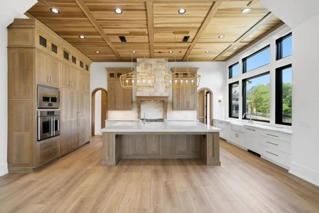 Symmetrical front perspective of a modern white oak and white kitchen layout featuring high-capacity appliance walls and a central stone top workstation.