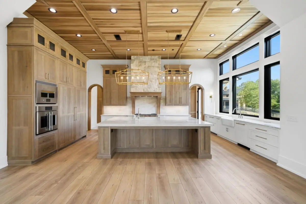 Symmetrical front perspective of a modern white oak and white kitchen layout featuring high-capacity appliance walls and a central stone top workstation.