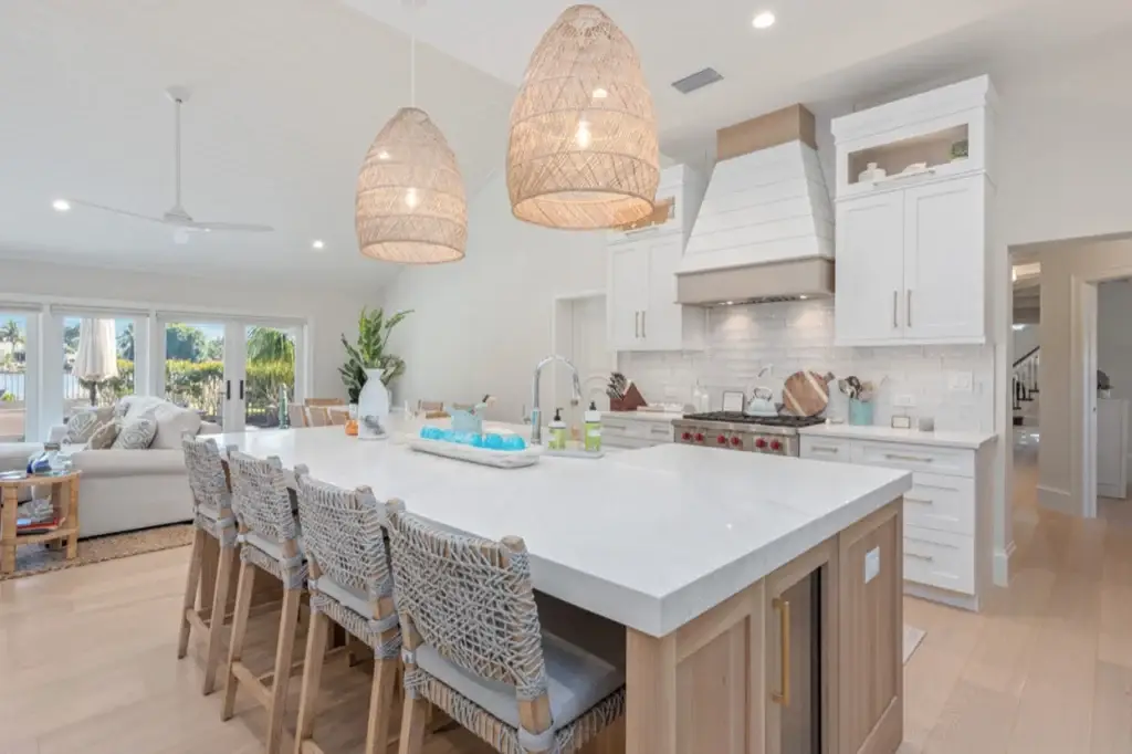 Luxury open-concept kitchen highlighting a custom white oak kitchen island with seating beneath large woven pendant lighting fixtures.