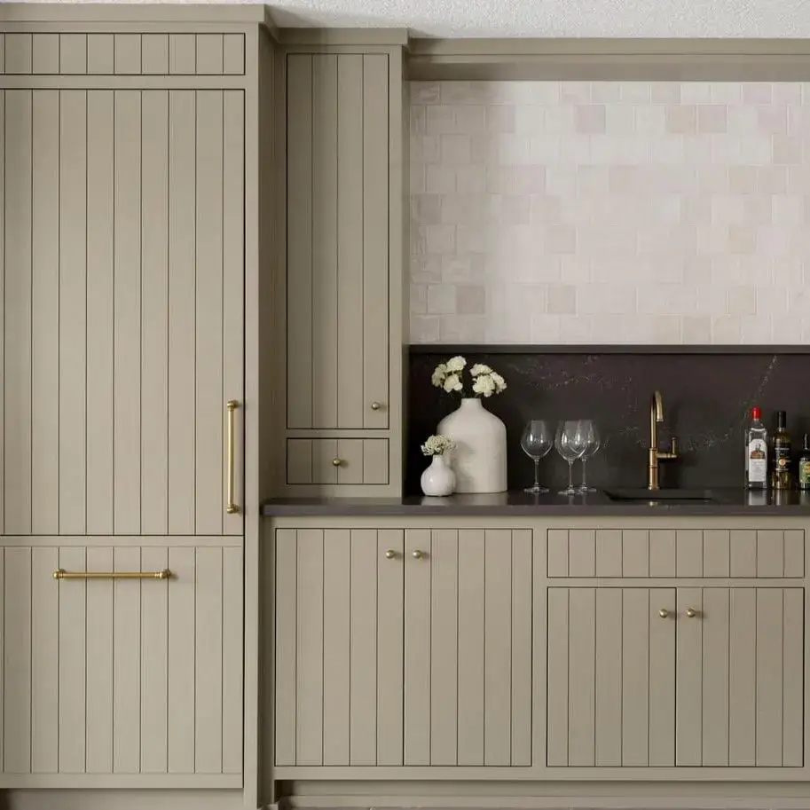 Custom kitchen cabinets featuring beadboard cabinet doors with vertical groove details in a soft light sage green painted finish.