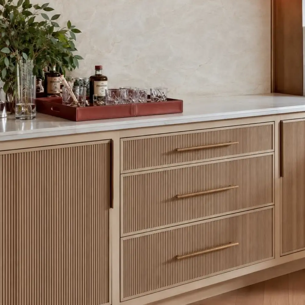 Close up view of precision-milled fluted cabinet doors in natural white oak with integrated brass shadow-line handles.