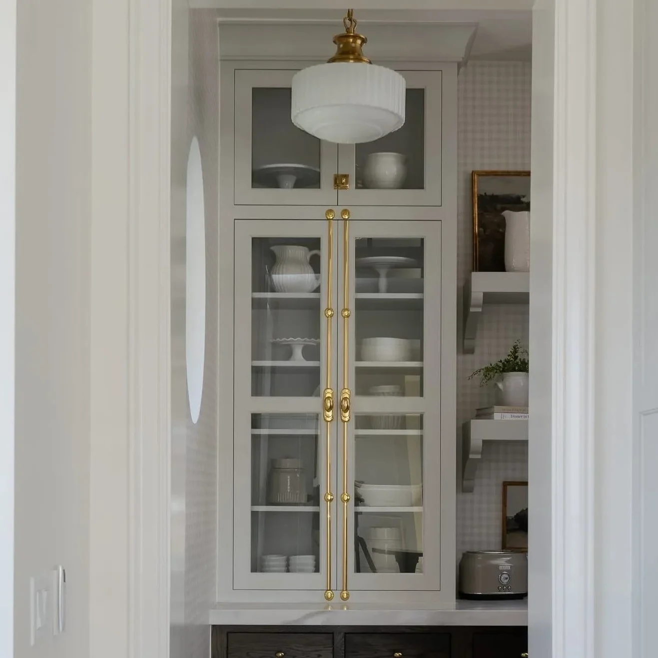 Upper kitchen cabinets featuring smoked glass cabinet doors set in ultra-slim matte black aluminum frames with warm interior LED shelf lighting.