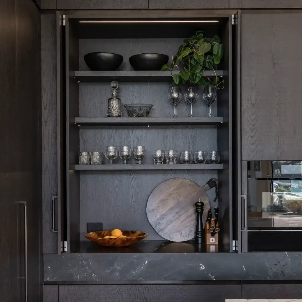Full-height pocket cabinet doors retracted into cabinet side pockets revealing an illuminated luxury home coffee and bar station.