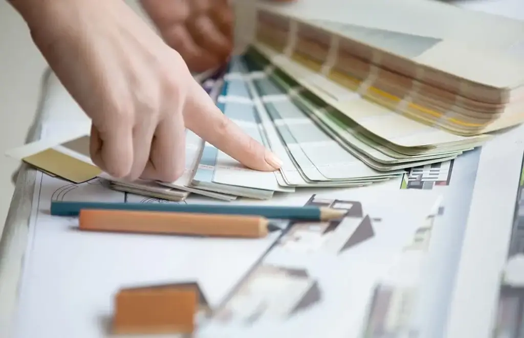 Interior designer selecting custom lacquer finish cabinets color swatches over architectural blueprints