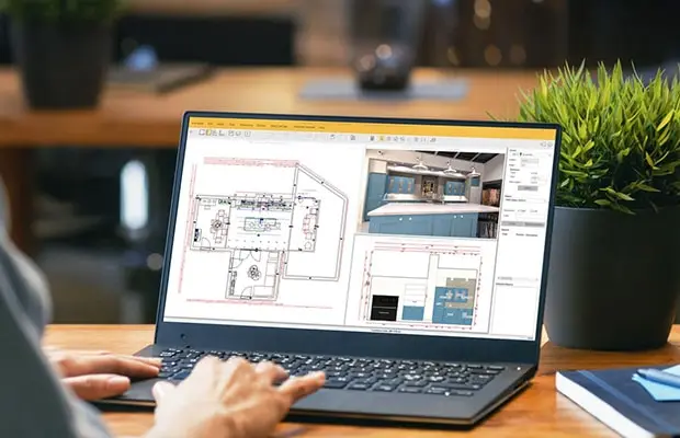 Architectural designer reviewing kitchen floor plans and 3D millwork drawings on a laptop for custom cabinetry pricing takeoff