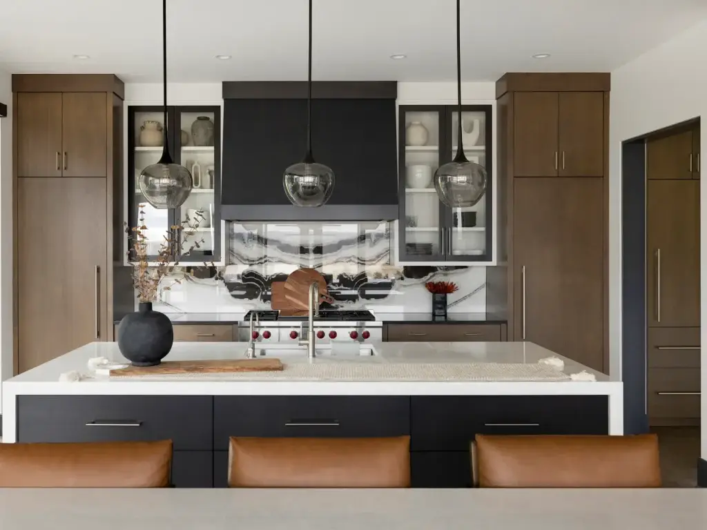Close detail of flat slab kitchen cabinets with wide blackened drawer banks and brass faucet.
