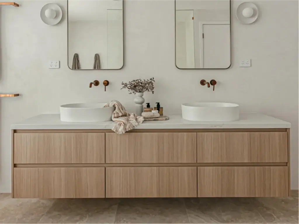 Modern wall-mounted floating double bathroom vanity with natural oak grain drawer fronts, white quartz countertop, dual vessel sinks, and matching mirrors.