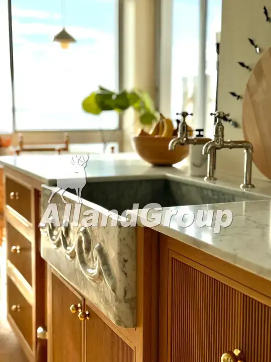 Hand-carved marble apron front sink integrated into fluted white oak cabinets