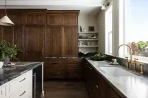 Floor-to-ceiling modern walnut kitchen cabinets with integrated panel-ready storage and contrasting white island