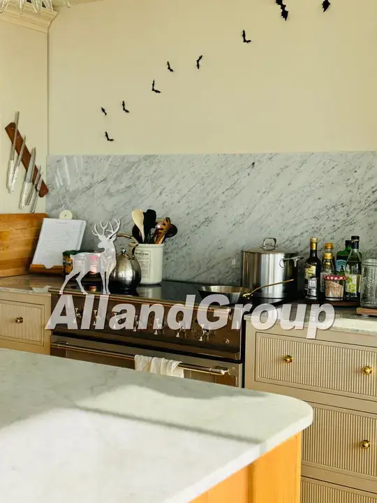 Slim shaker fluted drawers and marble backsplash around range cooktop in fluted white oak cabinets