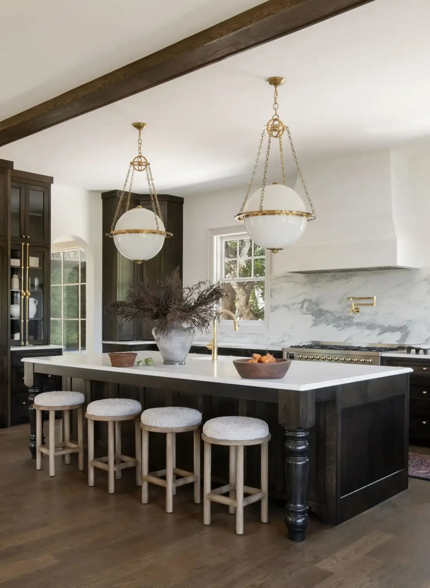 Contemporary dark wood kitchen cabinets island with marble countertops and brass globe pendants